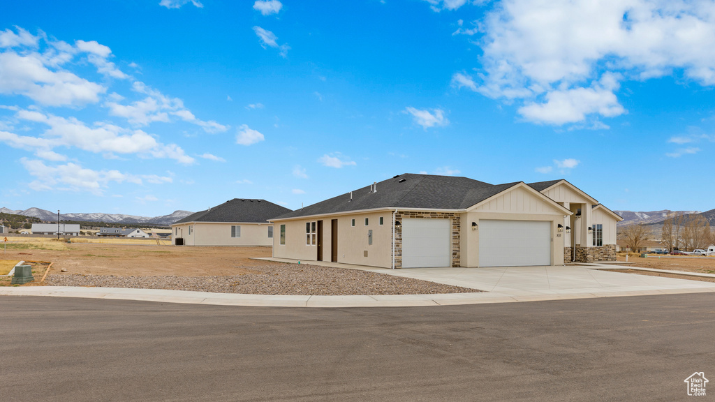 Ranch-style house featuring a mountain view, an attached garage, concrete driveway, and board and batten siding