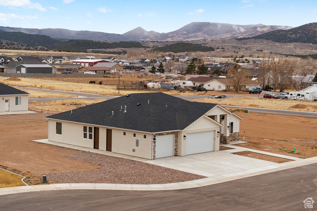 Exterior space with a mountain view, a residential view, concrete driveway, and an attached garage