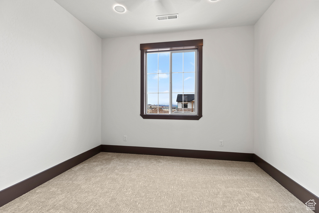 Carpeted spare room with visible vents and baseboards
