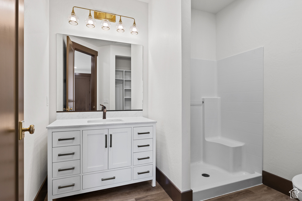 Full bath featuring vanity, wood finished floors, baseboards, a stall shower, and toilet