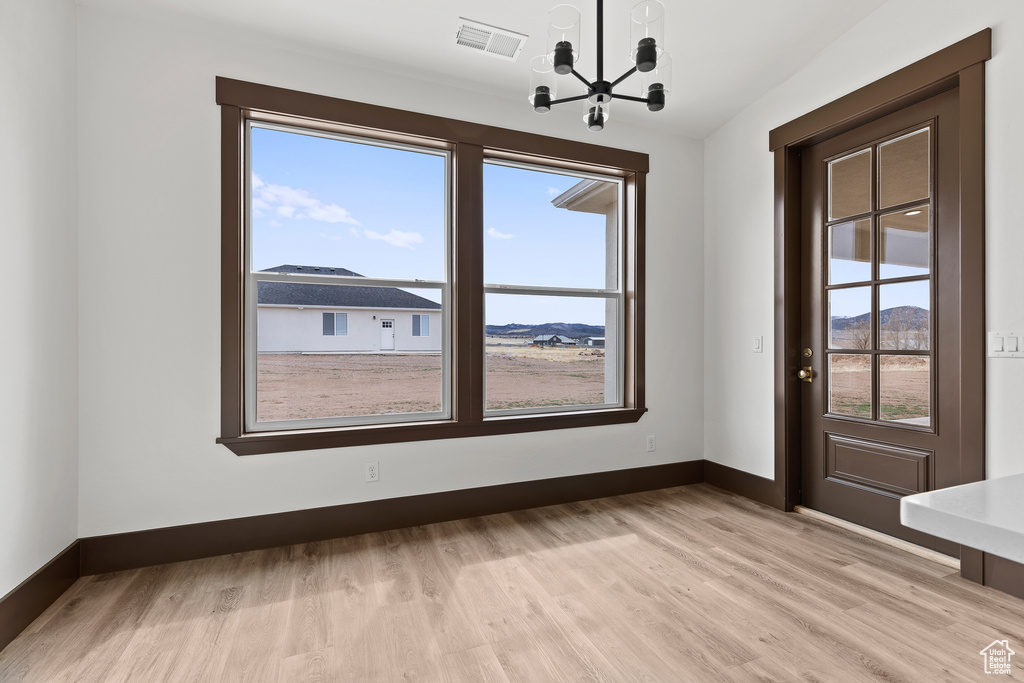 Interior space featuring a chandelier, visible vents, light wood-style flooring, and baseboards