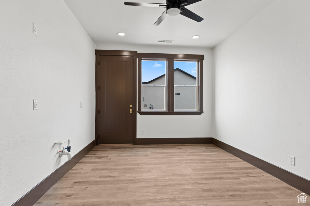 Empty room with visible vents, baseboards, light wood-style floors, and ceiling fan