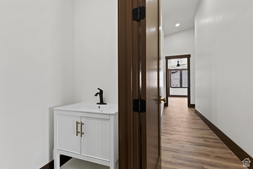 Corridor with recessed lighting, wood finished floors, baseboards, and a sink