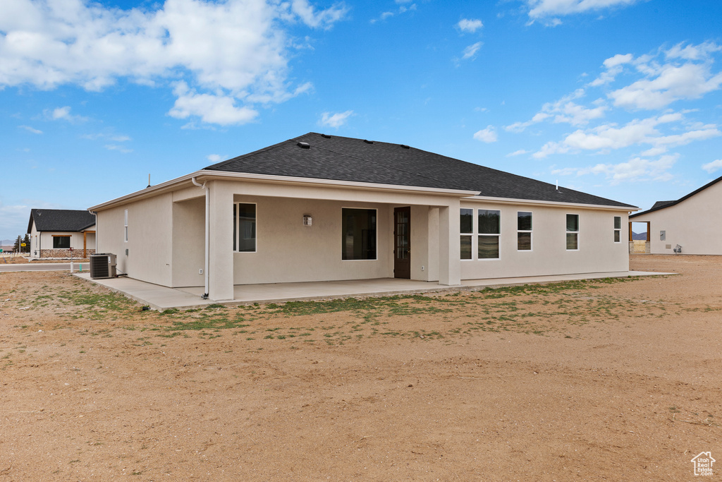 Rear view of house featuring central air condition unit, a patio, a shingled roof, and stucco siding