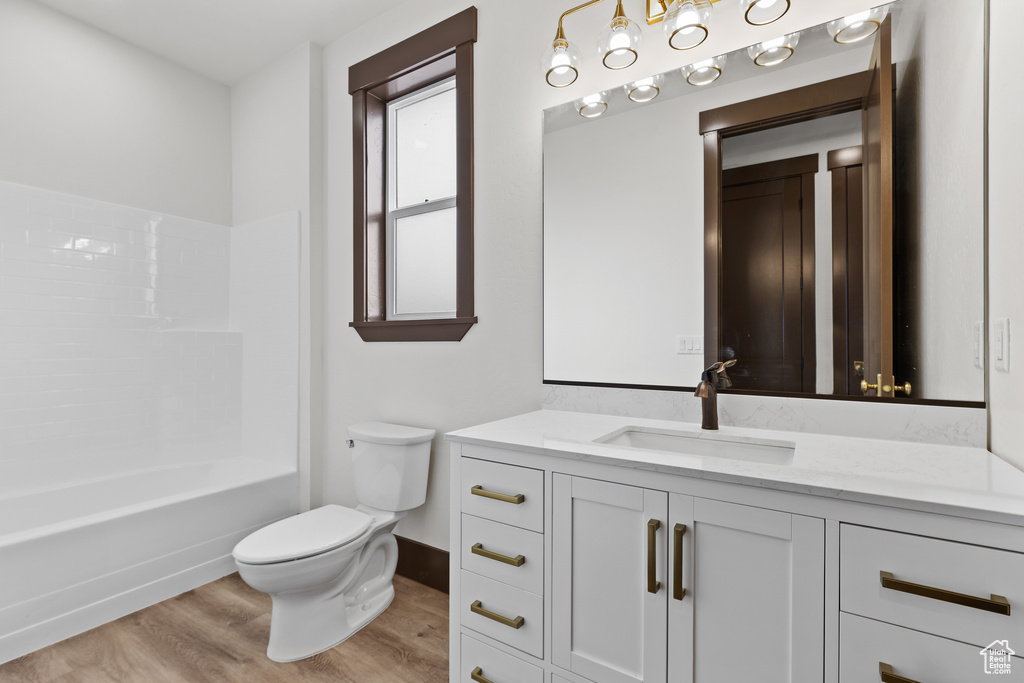 Bathroom featuring baseboards, toilet, wood finished floors, and vanity