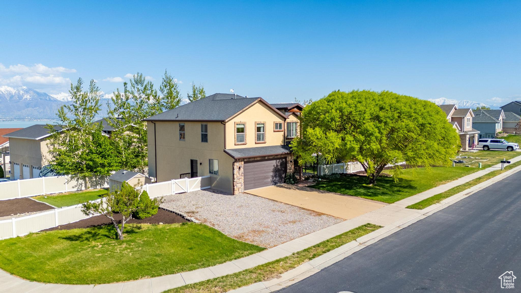 Traditional-style house featuring fence, a residential view, a garage, stucco siding, and driveway