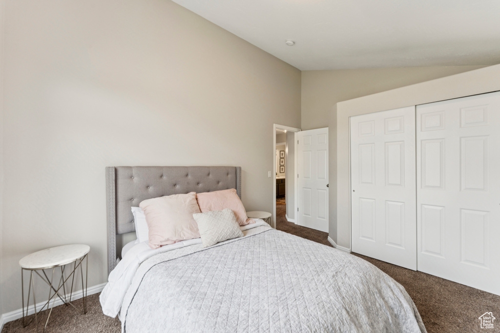Bedroom featuring vaulted ceiling, dark carpet, and a closet