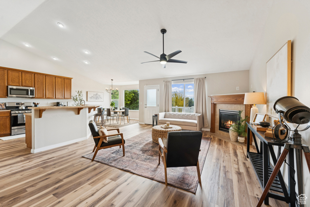Living room featuring lofted ceiling, ceiling fan, light wood-type flooring, a fireplace, and recessed lighting