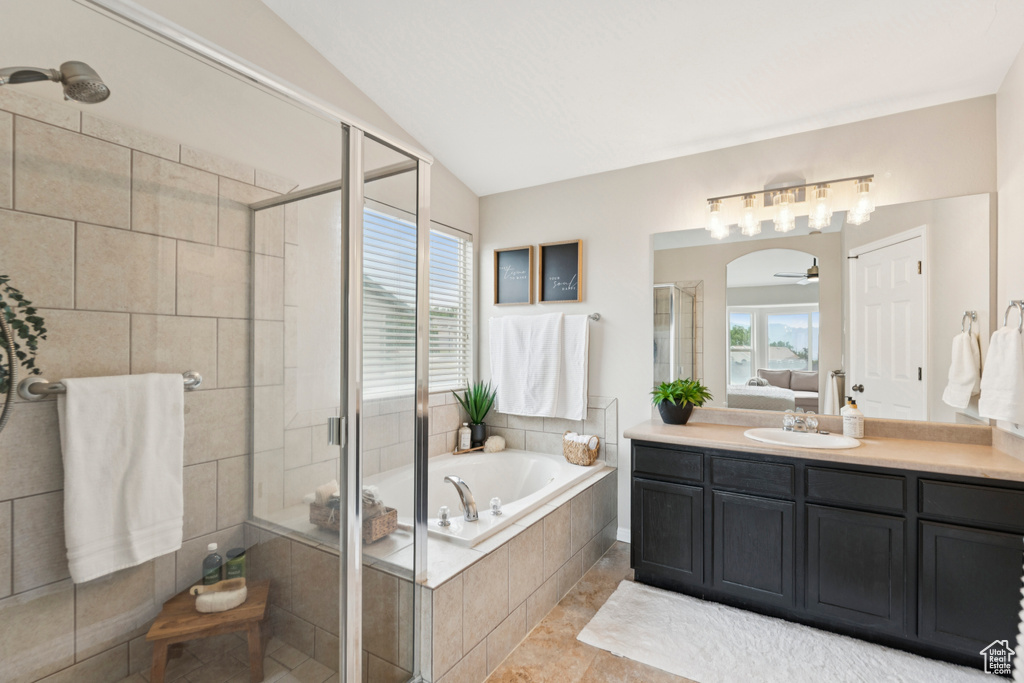 Ensuite bathroom with vanity, a stall shower, a bath, healthy amount of natural light, and vaulted ceiling