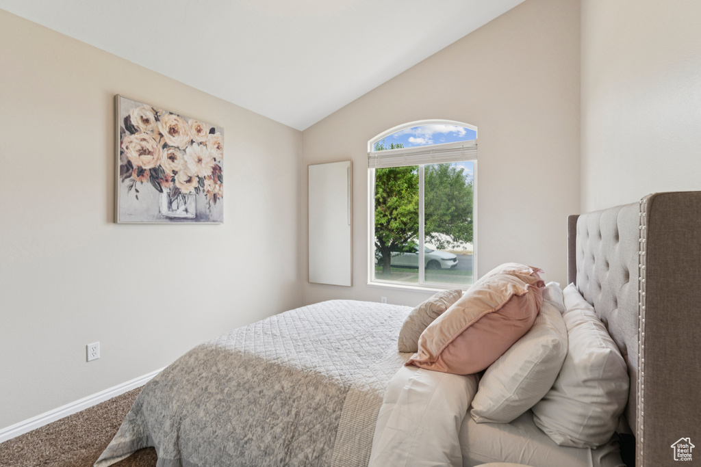 Carpeted bedroom featuring vaulted ceiling and baseboards