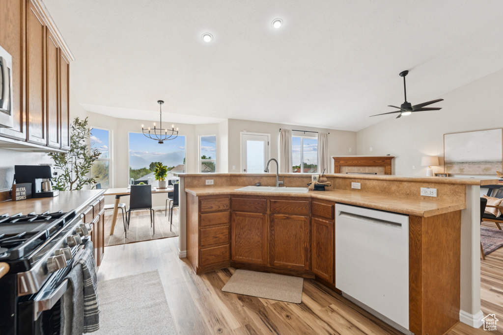 Kitchen featuring white dishwasher, a chandelier, light wood finished floors, stainless steel range with gas stovetop, and brown cabinetry