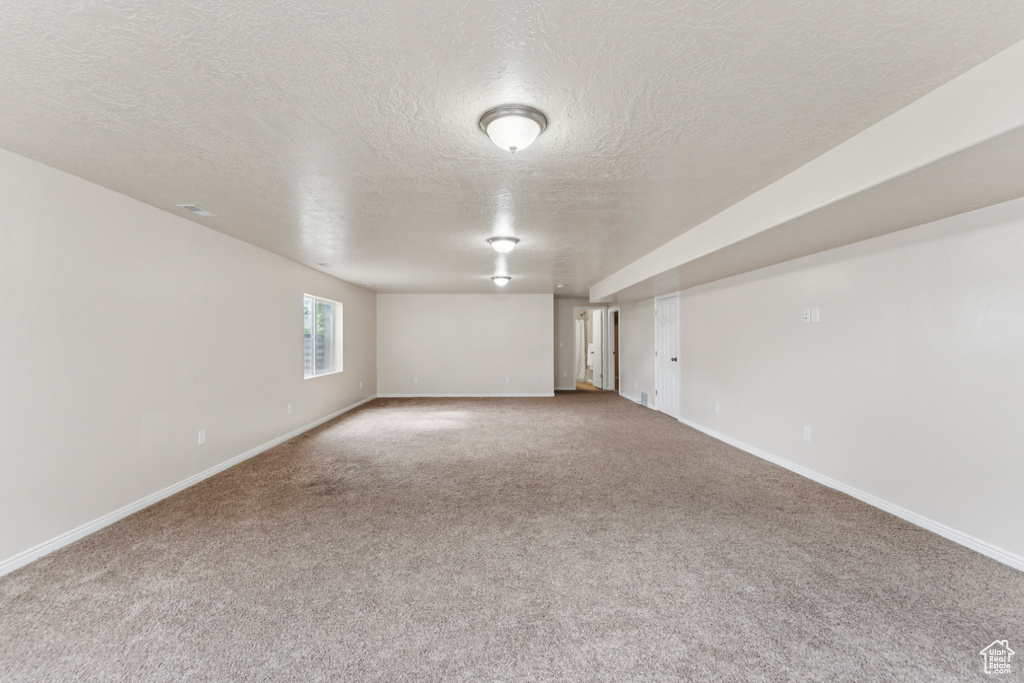 Carpeted spare room featuring a textured ceiling
