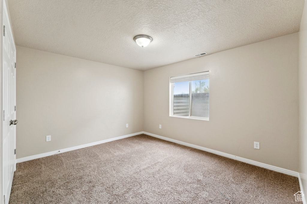 Empty room with carpet and a textured ceiling