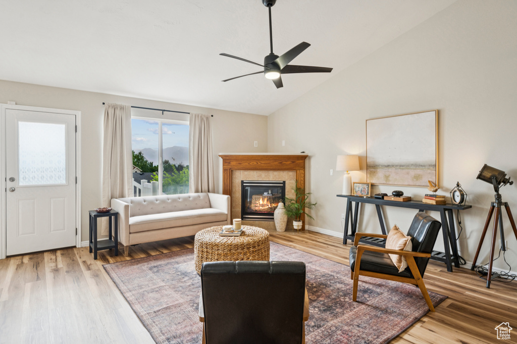 Living area featuring a ceiling fan, vaulted ceiling, wood finished floors, and a tile fireplace