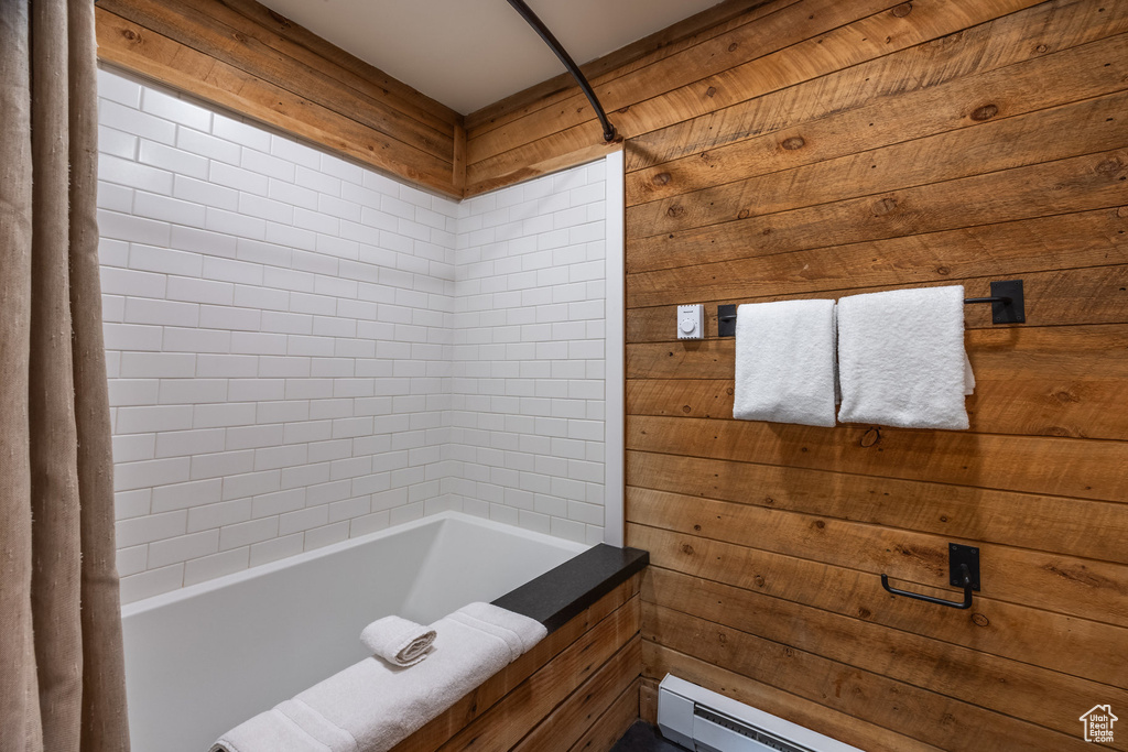 Full bathroom featuring a baseboard heating unit, wood walls, and bathing tub / shower combination