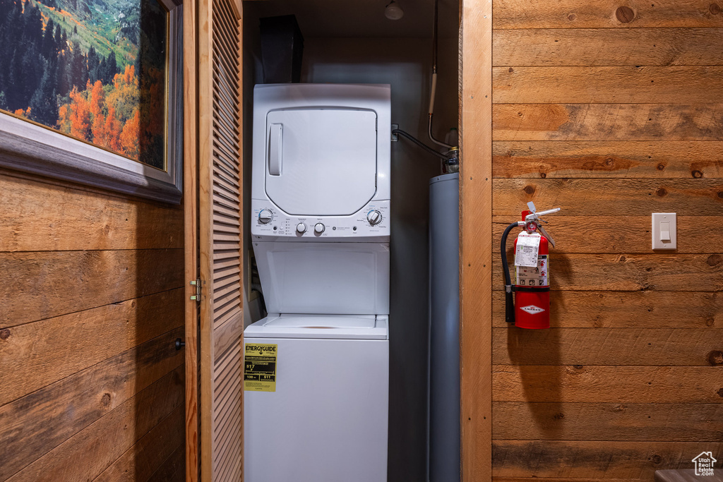 Washroom with stacked washer and clothes dryer and wood walls