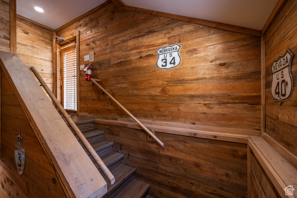 Stairs featuring wood walls, a relaxing sauna, and vaulted ceiling