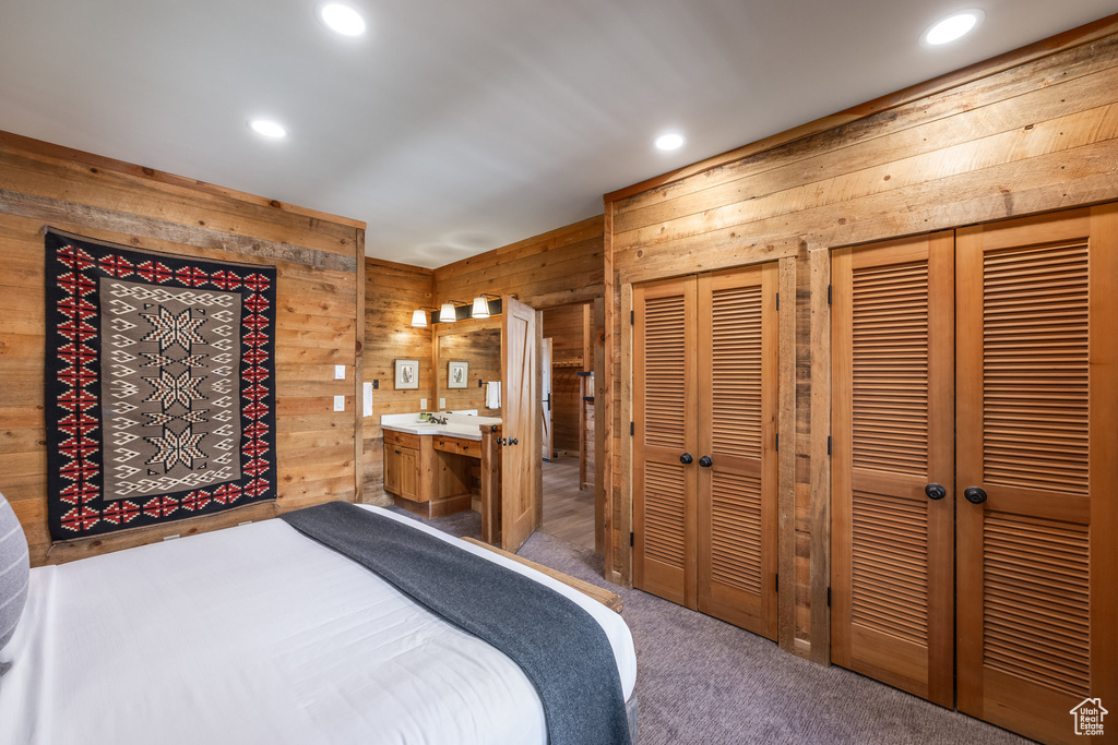 Bedroom with wooden walls, multiple closets, recessed lighting, carpet flooring, and ensuite bathroom