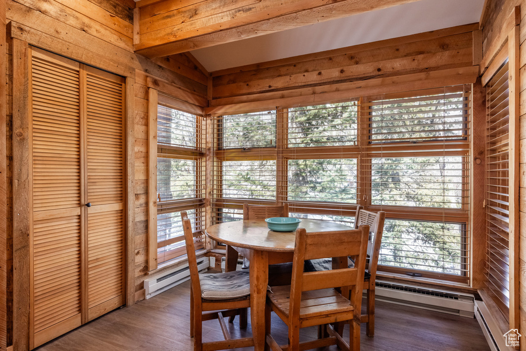Dining area with baseboard heating, wooden walls, wood finished floors, and a baseboard heating unit