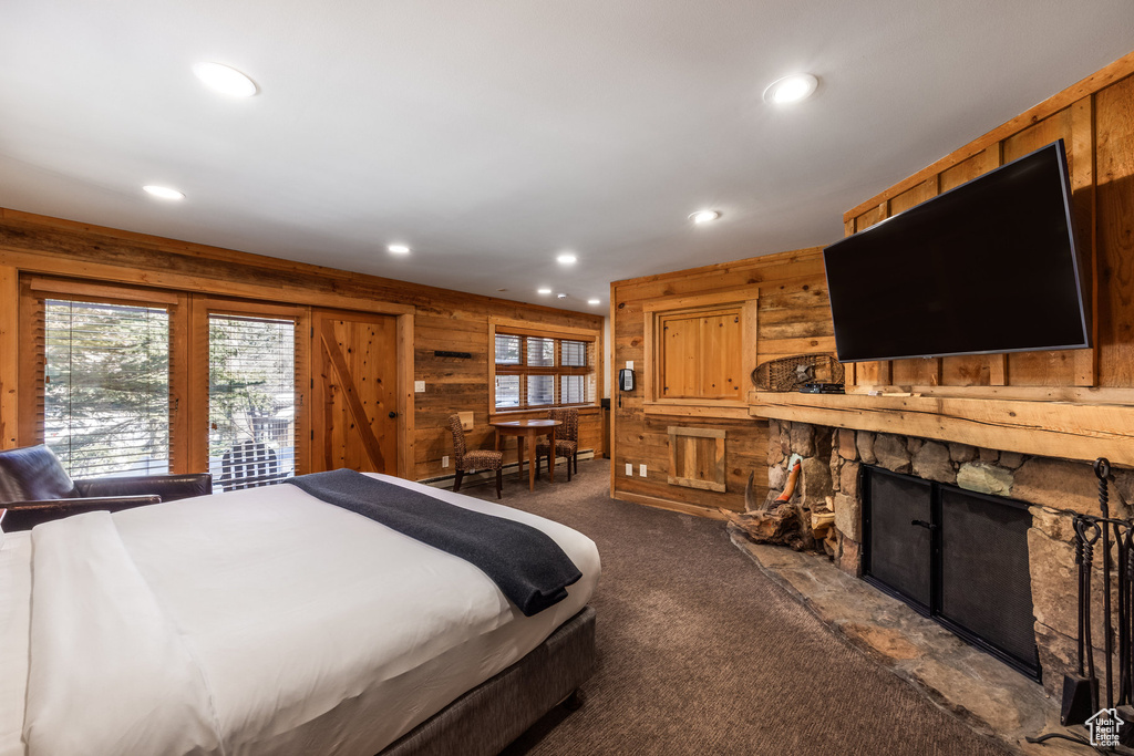 Bedroom with wood walls, recessed lighting, multiple windows, dark carpet, and a fireplace