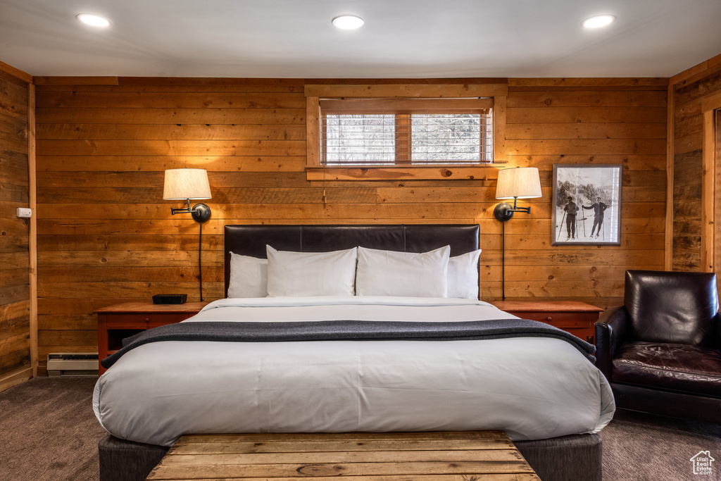Carpeted bedroom with baseboard heating, wooden walls, and recessed lighting