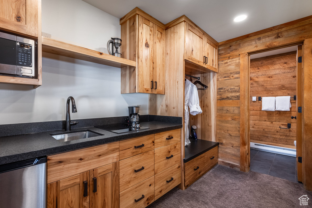 Kitchen with stainless steel appliances, a sink, wood walls, open shelves, and dark stone counters