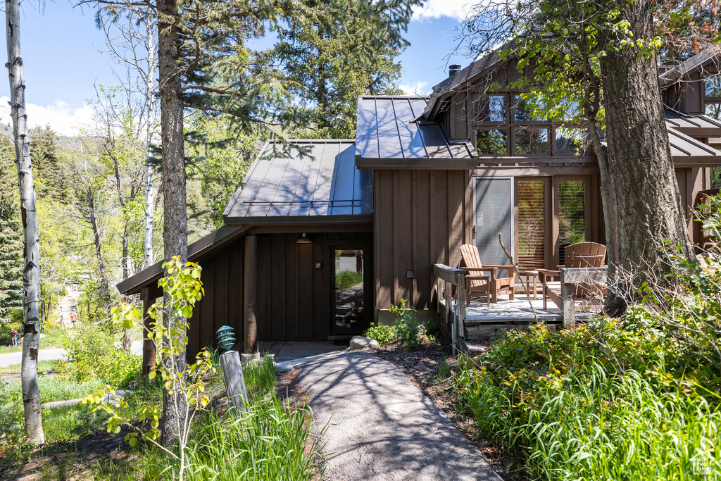 View of front of home with board and batten siding, a wooden deck, and metal roof