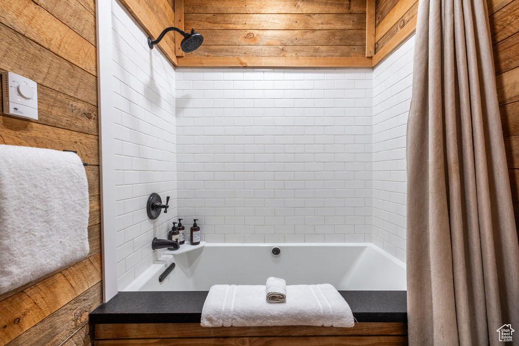 Bathroom featuring wooden walls and shower / tub combo with curtain