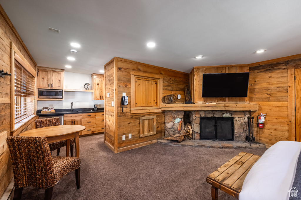 Living area with wood walls, dark colored carpet, a fireplace, and recessed lighting