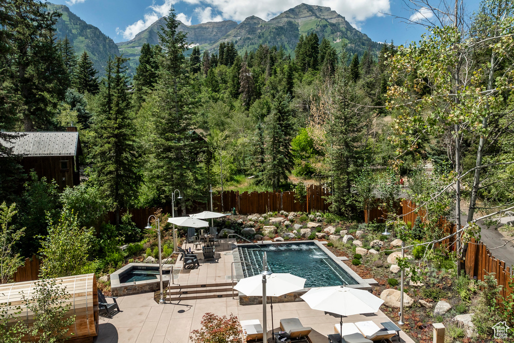 View of pool with a fenced backyard, outdoor dining space, a mountain view, a patio, and a view of trees