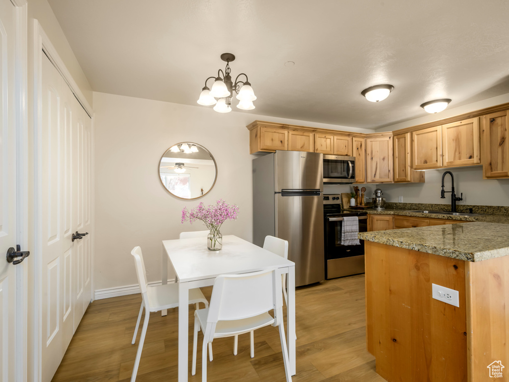 Kitchen with a chandelier, stainless steel appliances, light wood-type flooring, and a sink