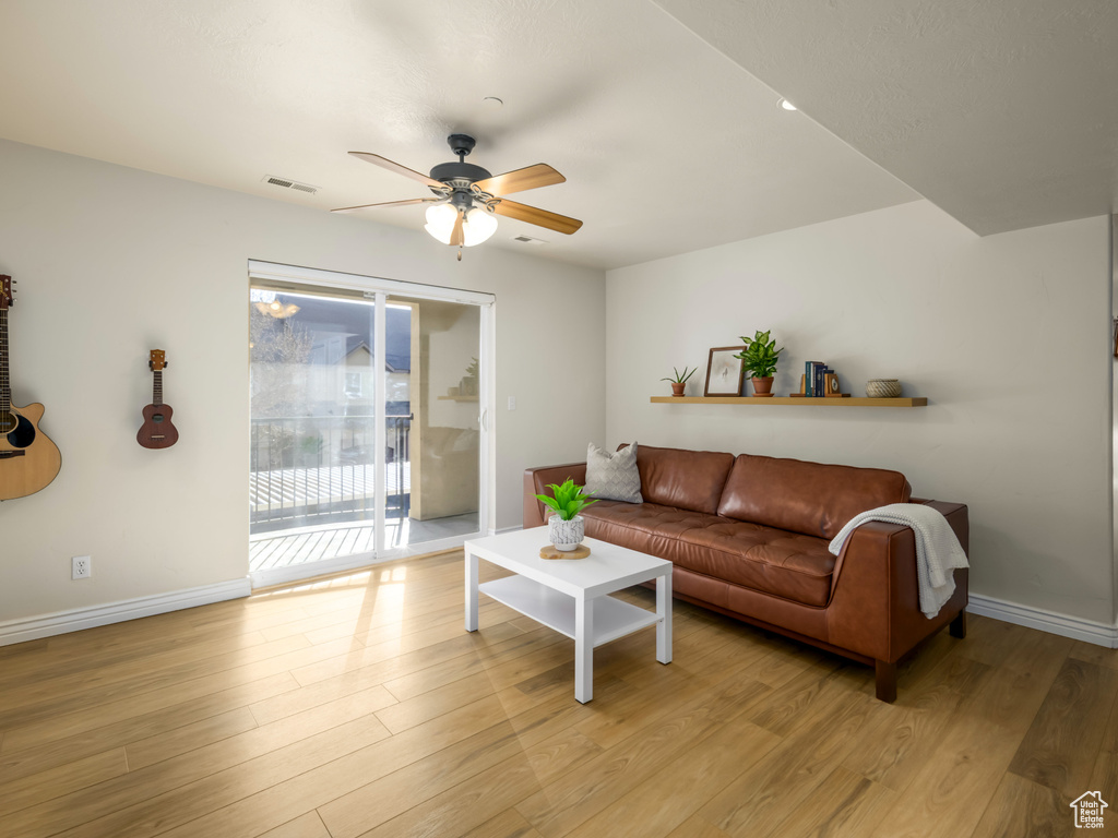 Living room with visible vents, baseboards, ceiling fan, and light wood finished floors