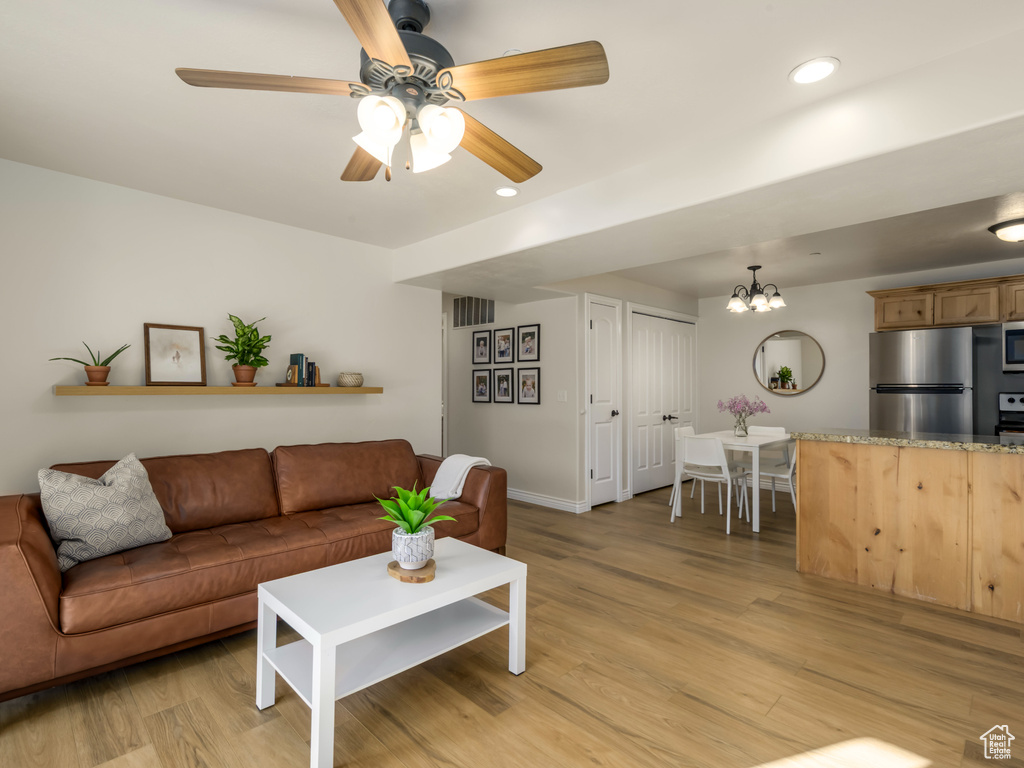 Living room with ceiling fan with notable chandelier, light wood-style flooring, recessed lighting, and visible vents