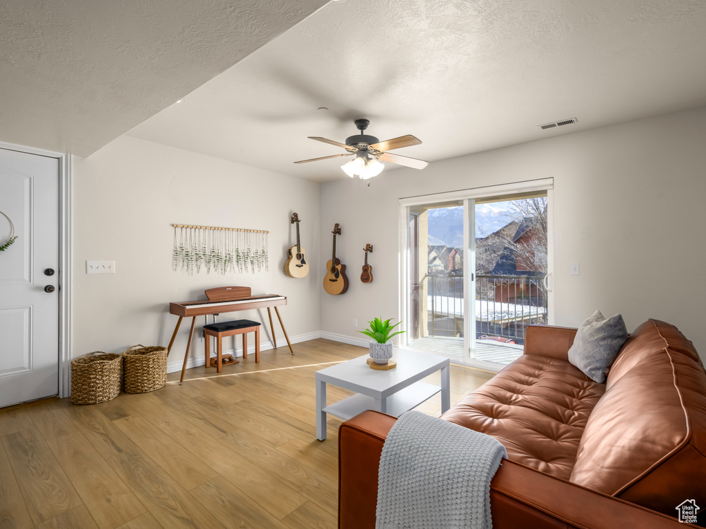 Living area featuring visible vents, a textured ceiling, light wood-type flooring, and ceiling fan