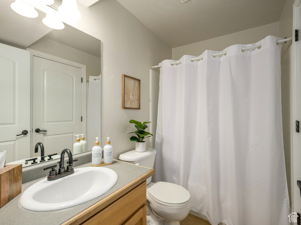 Bathroom with a shower with shower curtain, toilet, and vanity