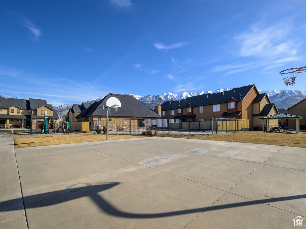 View of sport court featuring fence, a residential view, playground community, community basketball court, and a mountain view