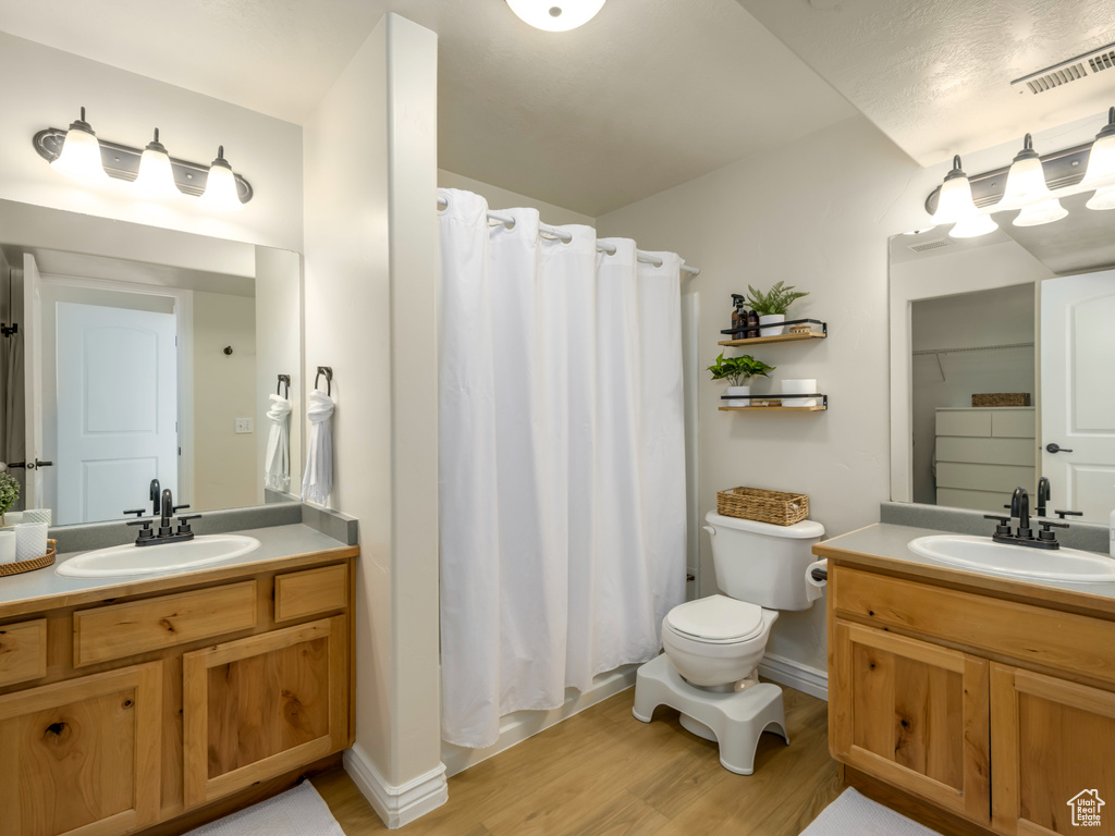 Full bath with two vanities, visible vents, and a sink