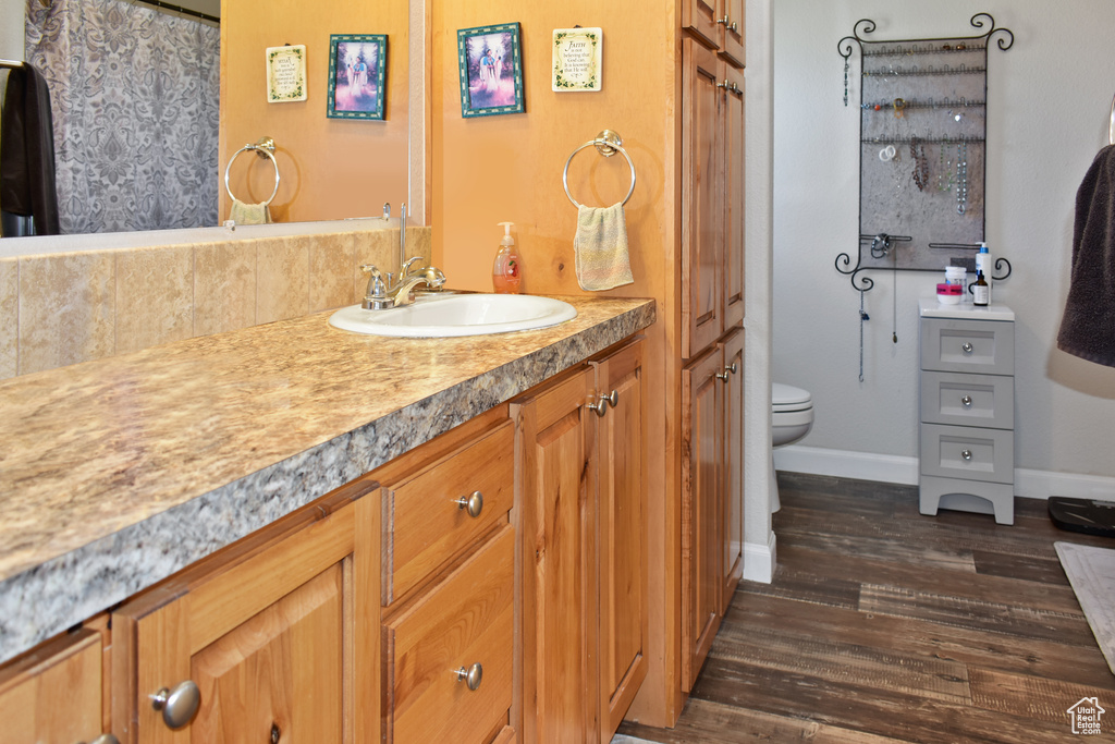 Full bath featuring baseboards, toilet, wood finished floors, and vanity