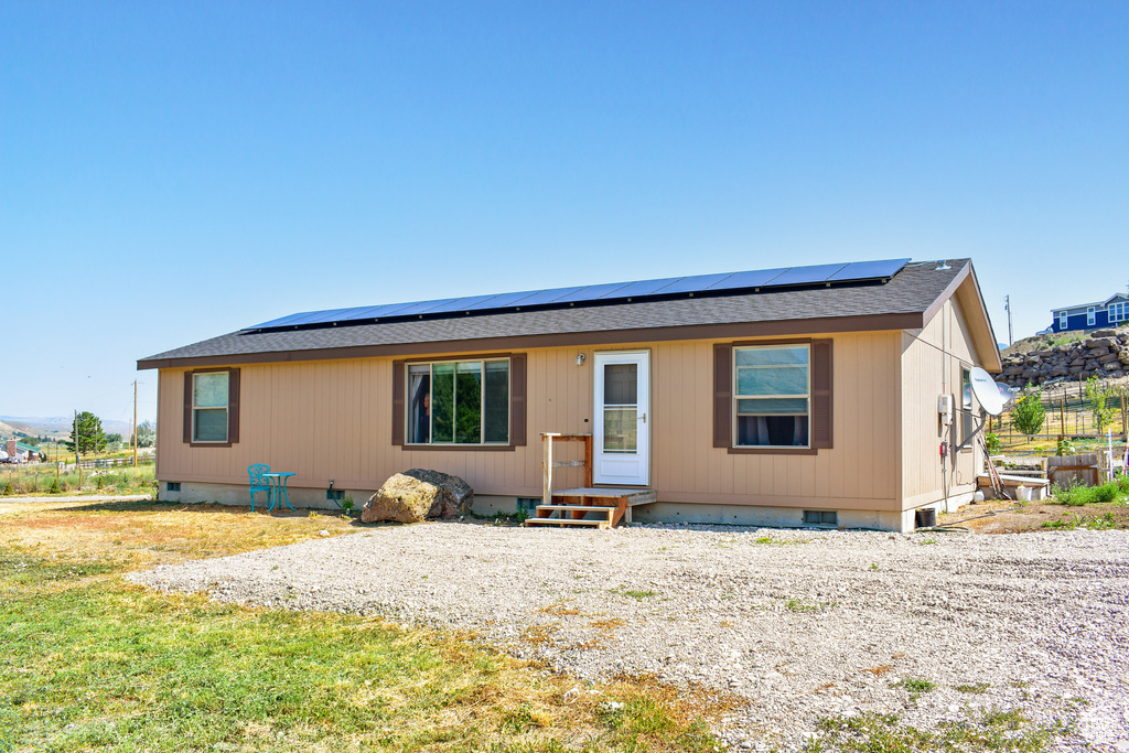 View of front of home featuring crawl space, solar panels, a shingled roof, and entry steps