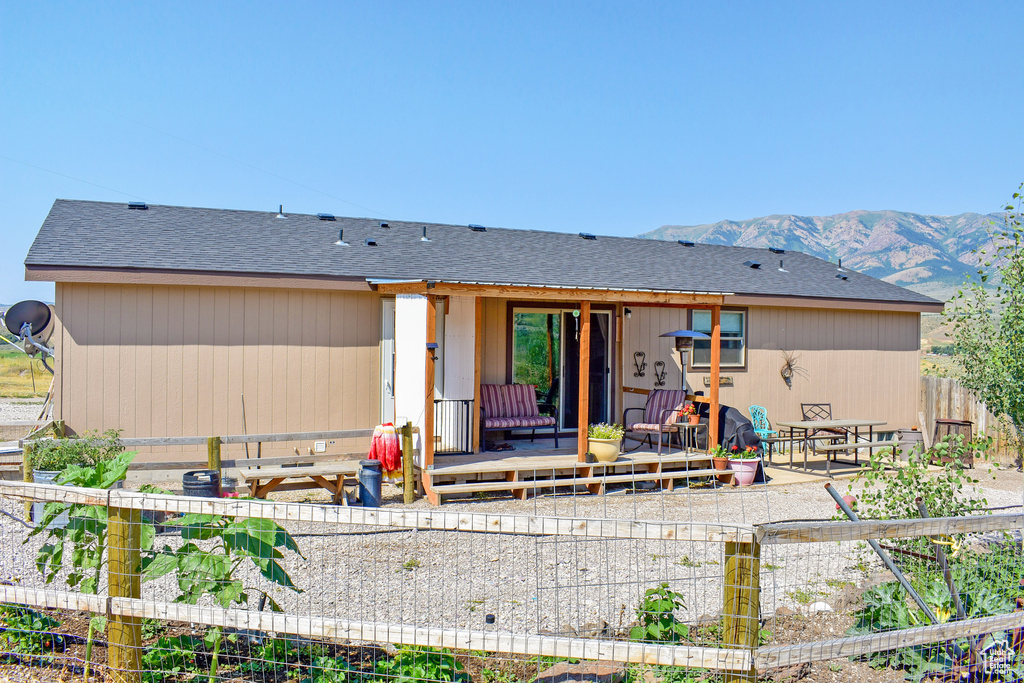 Rear view of property featuring a mountain view, a shingled roof, a patio, and fence