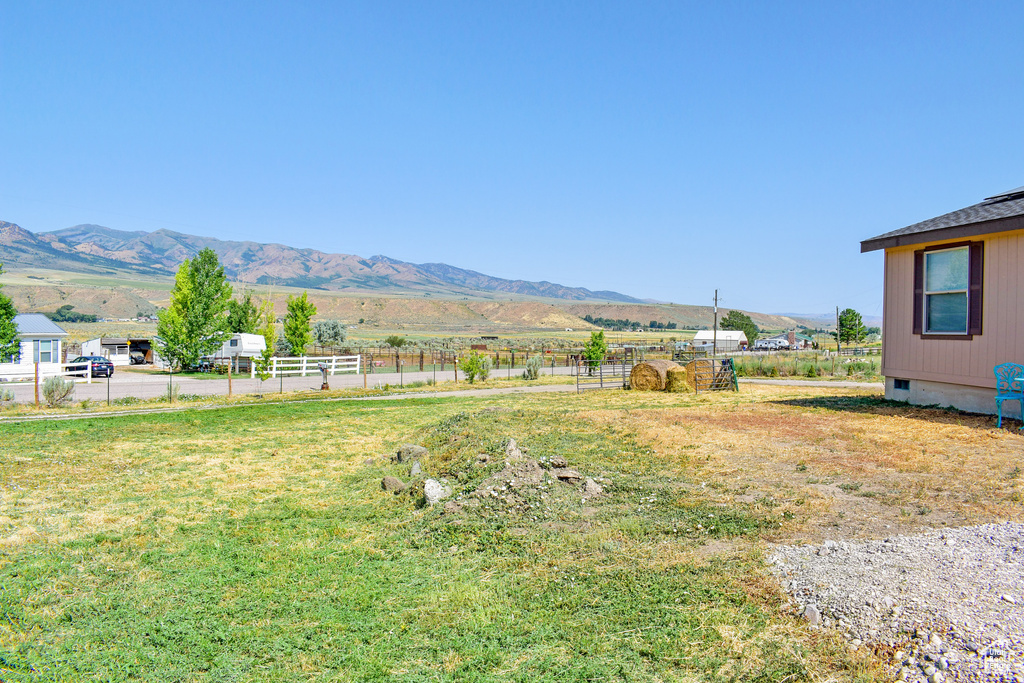 View of yard featuring a rural view, a mountain view, and fence