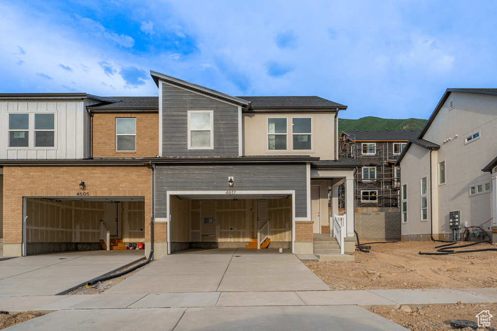 View of front of home with a garage, driveway, brick siding, and board and batten siding