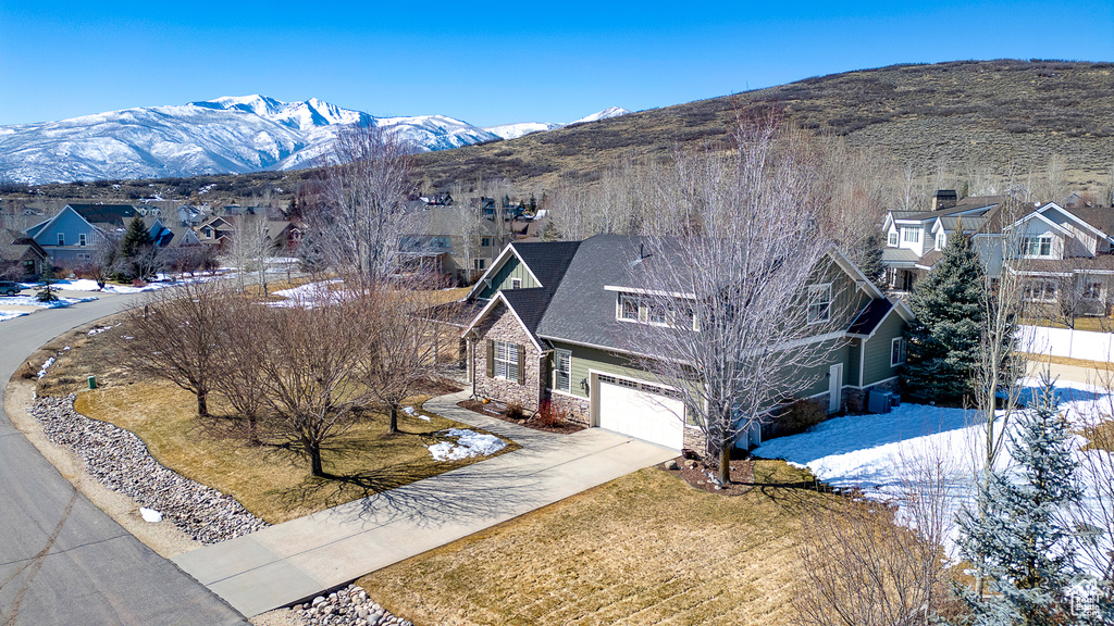Exterior space featuring driveway, stone siding, a mountain view, a residential view, and an attached garage