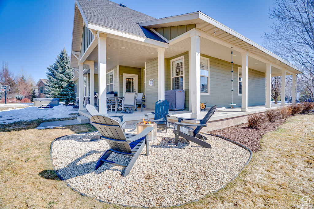 Rear view of house with a patio, board and batten siding, a shingled roof, and an outdoor fire pit