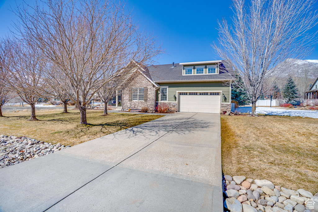 View of front of property with stone siding, driveway, and a front lawn