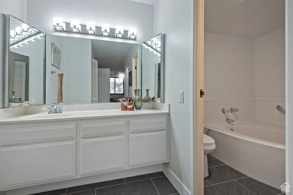 Bathroom featuring vanity, a garden tub, baseboards, tile patterned floors, and toilet