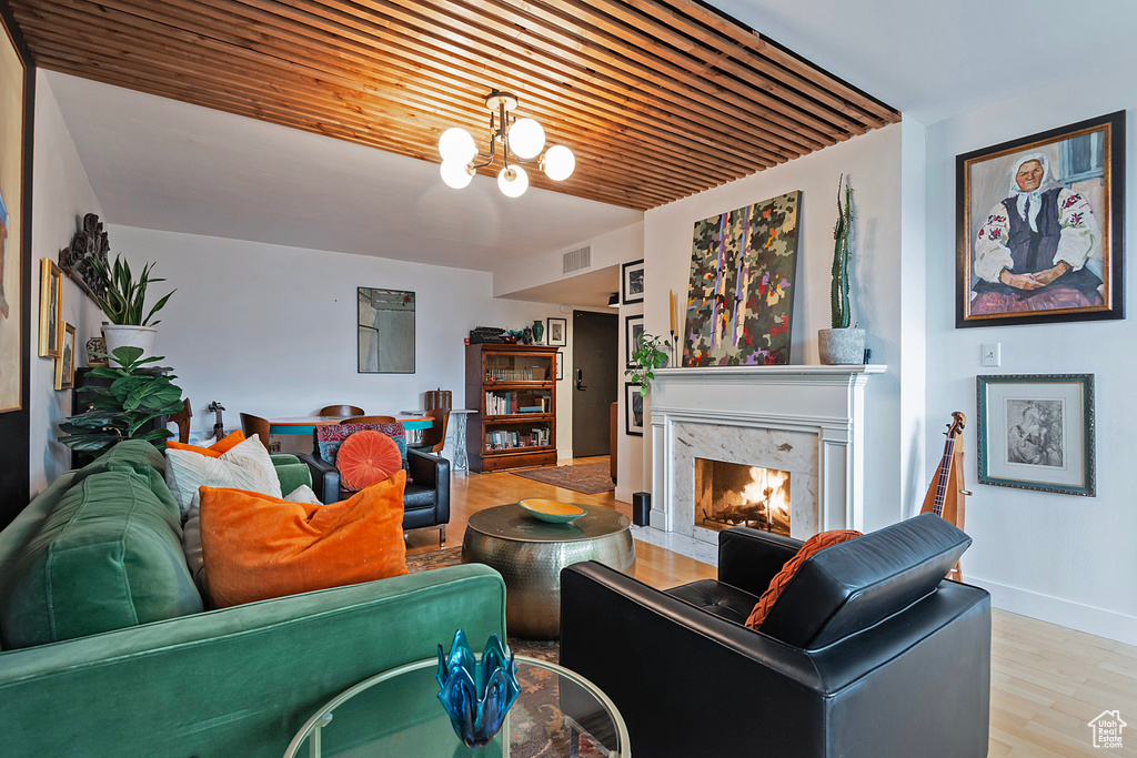 Living area with visible vents, a notable chandelier, wood finished floors, a high end fireplace, and baseboards