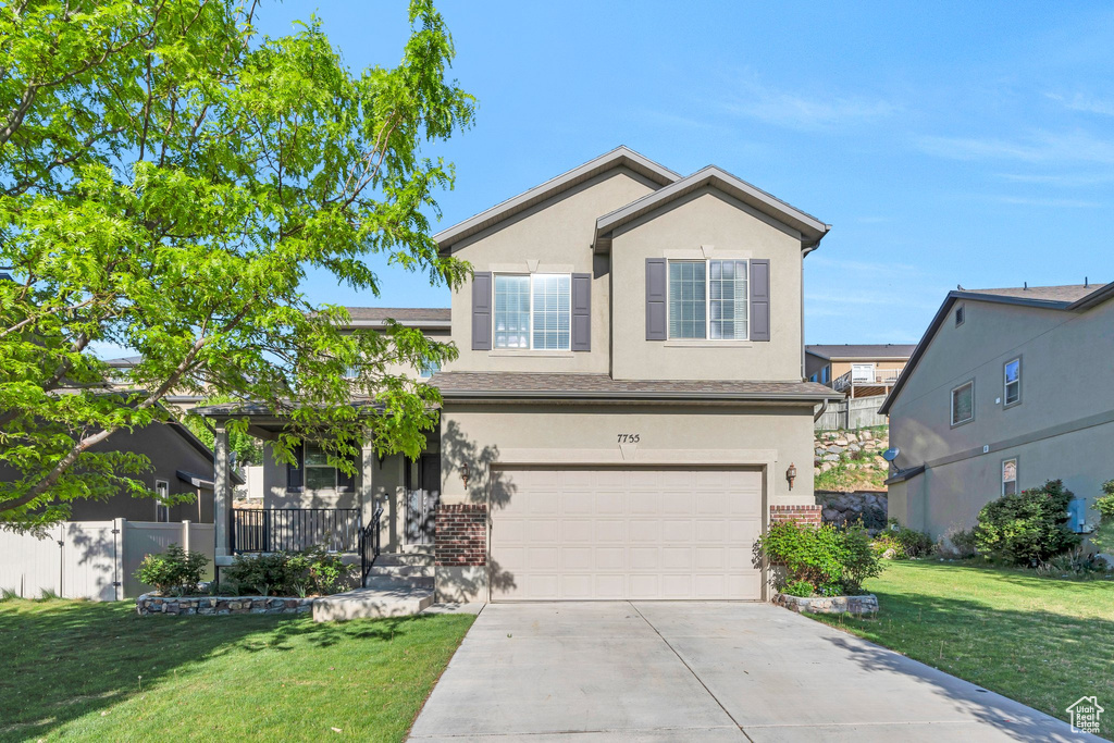 Traditional-style house featuring a garage, stucco siding, concrete driveway, brick siding, and covered porch