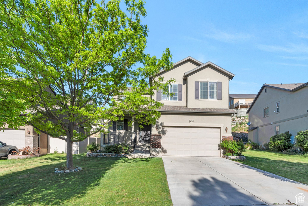View of front of house featuring driveway, an attached garage, a front yard, brick siding, and stucco siding
