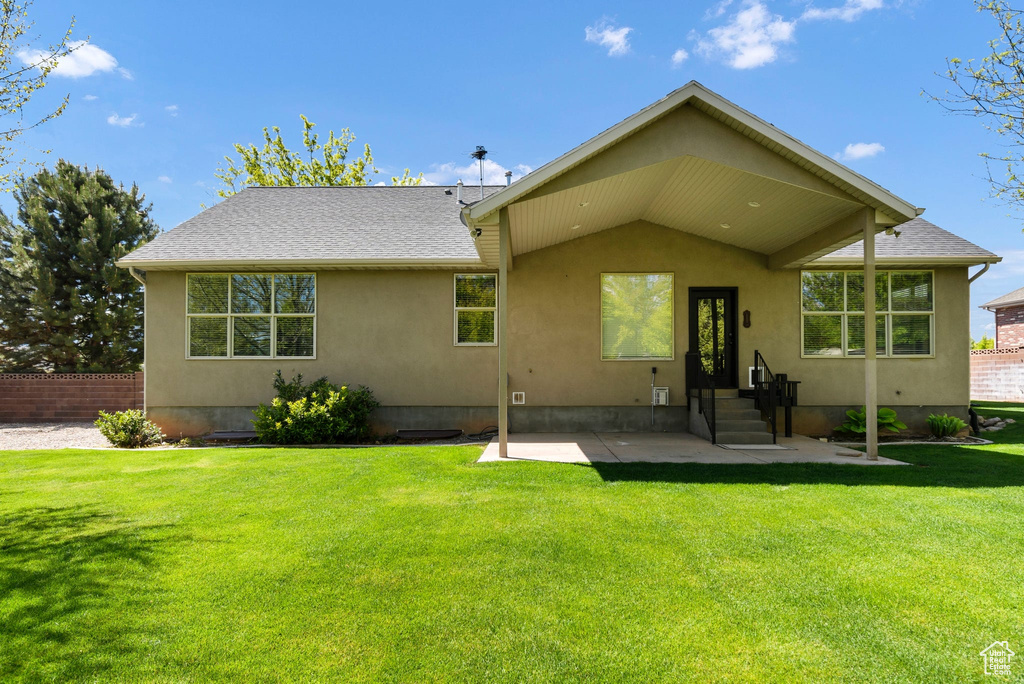 Back of property with a patio, stucco siding, and a lawn